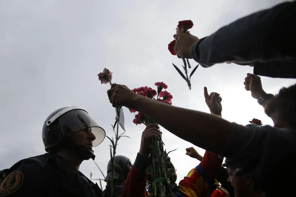 Several people show carnations to the policemen who surround the voting center of Sant Juliá de Ramis (Francisco Seco / AP Photo) Several people show carnations to the policemen who surround the voting center of Sant Juliá de Ramis (Francisco Seco / AP Photo)